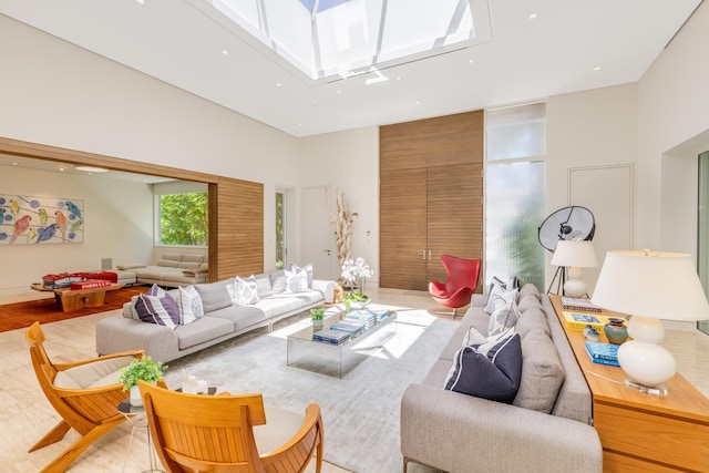 living room featuring a towering ceiling and a skylight