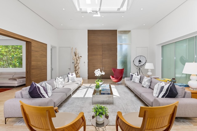 living room featuring a skylight, a high ceiling, and light hardwood / wood-style floors