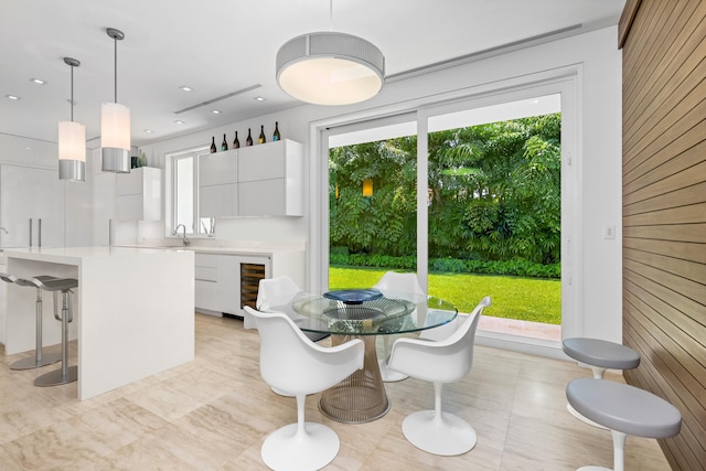 dining space featuring a wealth of natural light, beverage cooler, and wooden walls