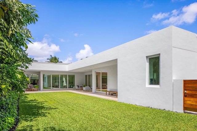 rear view of house featuring a yard and a patio