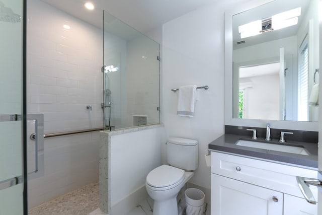 bathroom with a tile shower, vanity, and toilet