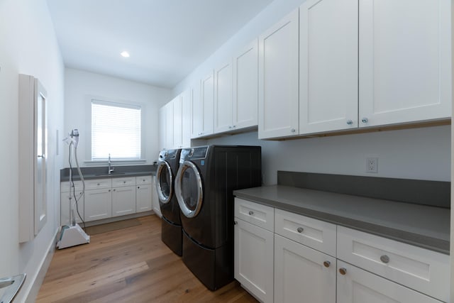 laundry room featuring light wood-type flooring, sink, independent washer and dryer, and cabinets