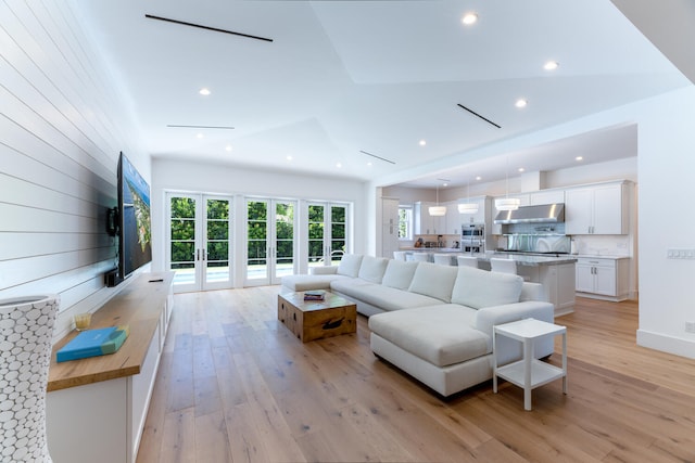 living room featuring french doors, wood walls, and light hardwood / wood-style floors