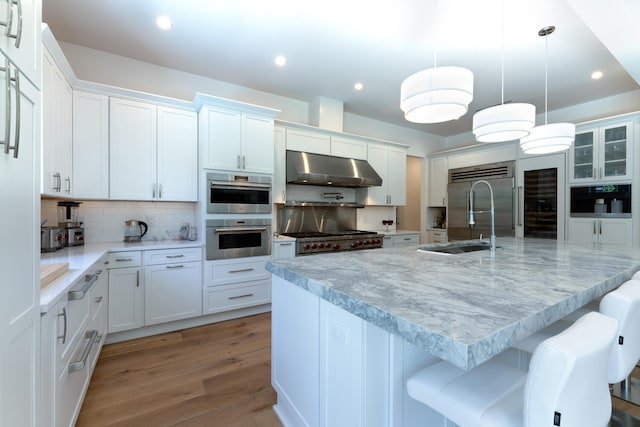 kitchen with white cabinets, decorative light fixtures, light wood-type flooring, and extractor fan