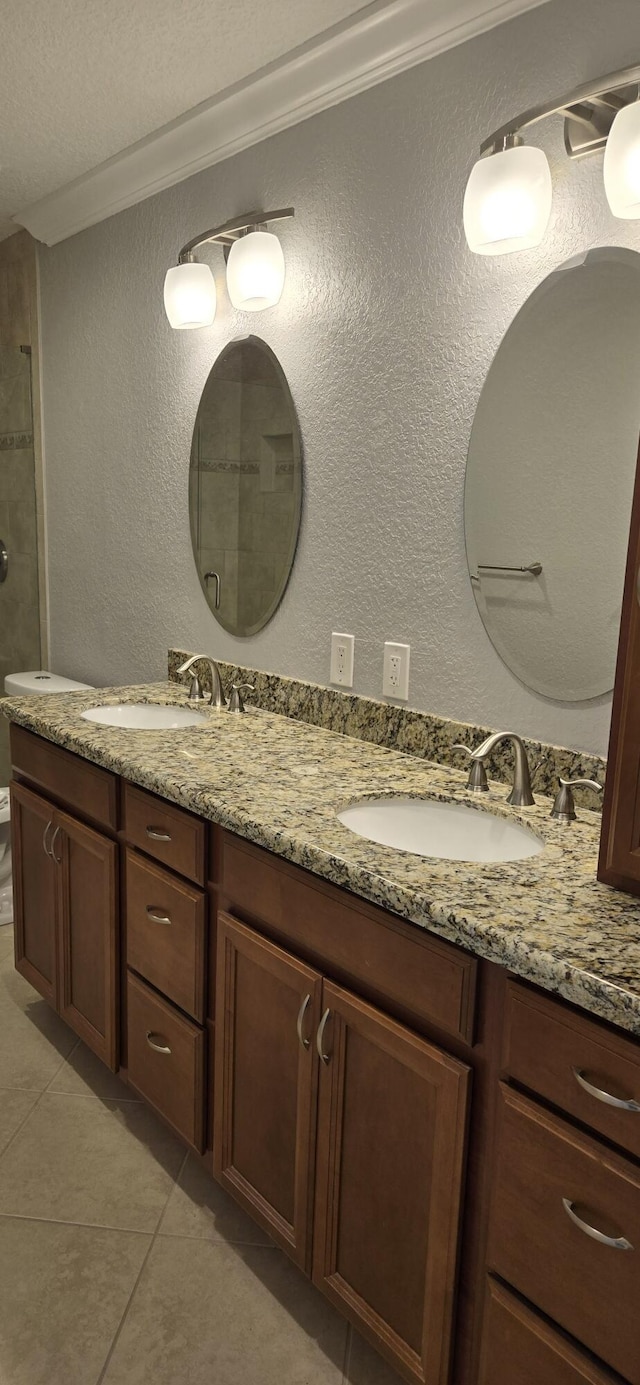 bathroom featuring a textured ceiling, vanity, ornamental molding, and tile patterned floors