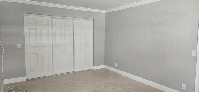 184 Burgundy D, Delray Beach, FL 33484 - unfurnished bedroom with ornamental molding, a closet, baseboards, and tile patterned floors