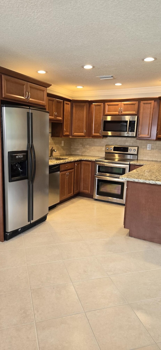 kitchen featuring appliances with stainless steel finishes, light stone counters, and light tile patterned floors