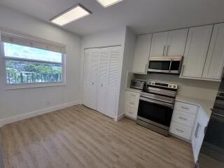 kitchen with light wood-type flooring, stainless steel appliances, and white cabinets