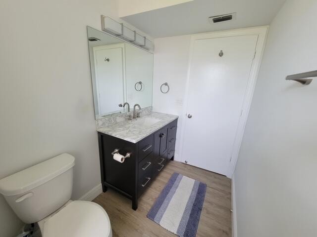 bathroom with vanity, toilet, and hardwood / wood-style flooring