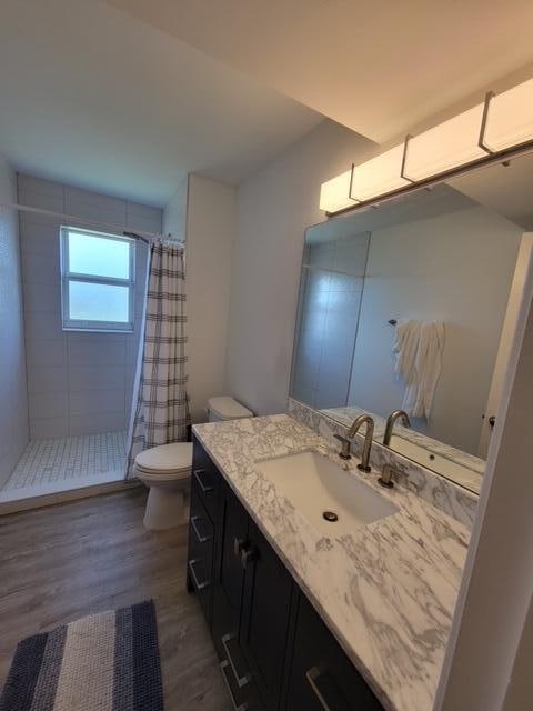 bathroom with walk in shower, toilet, hardwood / wood-style flooring, and vanity