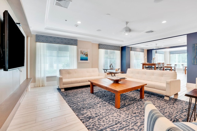 living room with a raised ceiling, ceiling fan, and light hardwood / wood-style floors