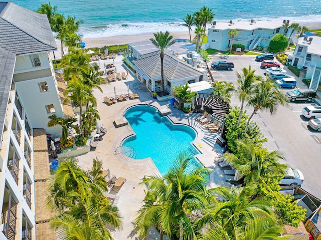 view of pool featuring a patio, a water view, and a beach view