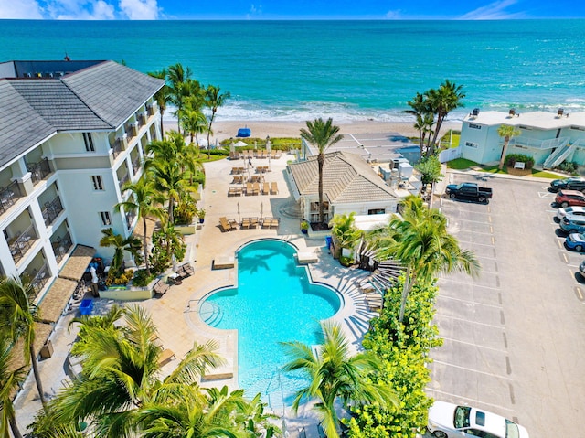 view of swimming pool featuring a patio area, a water view, and a view of the beach