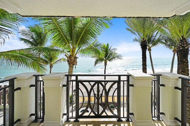 balcony with a water view and a view of the beach