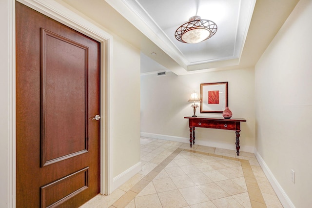 entrance foyer with light tile patterned floors, a tray ceiling, and ornamental molding