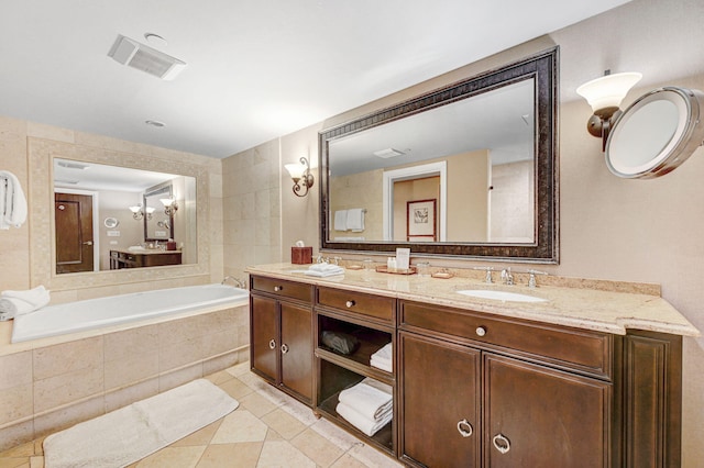 bathroom with tile patterned flooring, tiled tub, and vanity