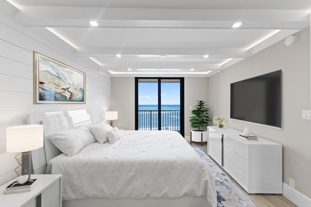 bedroom with beamed ceiling, light wood-type flooring, and access to outside