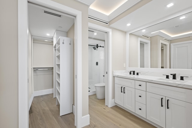 bathroom with a tile shower, toilet, vanity, and hardwood / wood-style flooring