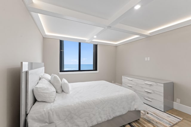 bedroom with beamed ceiling, coffered ceiling, and light wood-type flooring