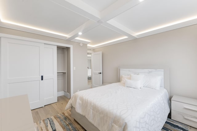 bedroom with coffered ceiling, beam ceiling, light hardwood / wood-style flooring, and a closet