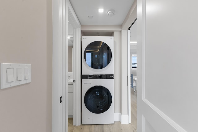 washroom with light wood-type flooring and stacked washer and clothes dryer