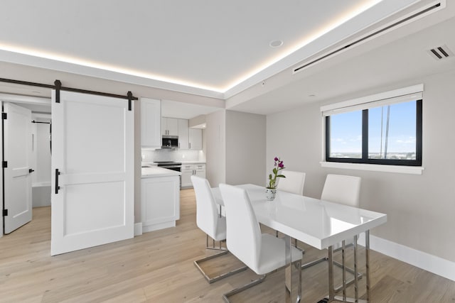 dining area featuring a barn door and light hardwood / wood-style floors