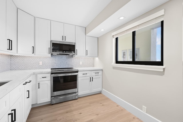 kitchen featuring backsplash, stainless steel appliances, white cabinetry, and light hardwood / wood-style flooring