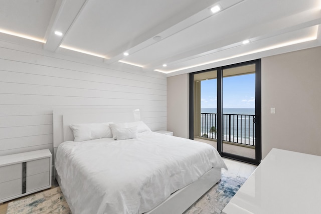 bedroom with access to exterior, a water view, beamed ceiling, and light hardwood / wood-style flooring