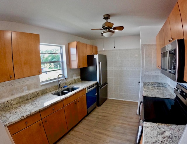 kitchen featuring light hardwood / wood-style flooring, stainless steel appliances, sink, ceiling fan, and tile walls