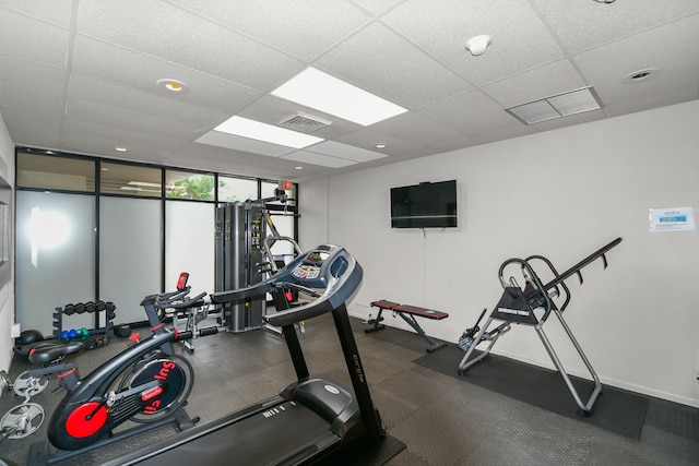 gym featuring a paneled ceiling and a wall of windows