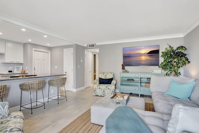 living room with light wood-style flooring, baseboards, ornamental molding, and recessed lighting