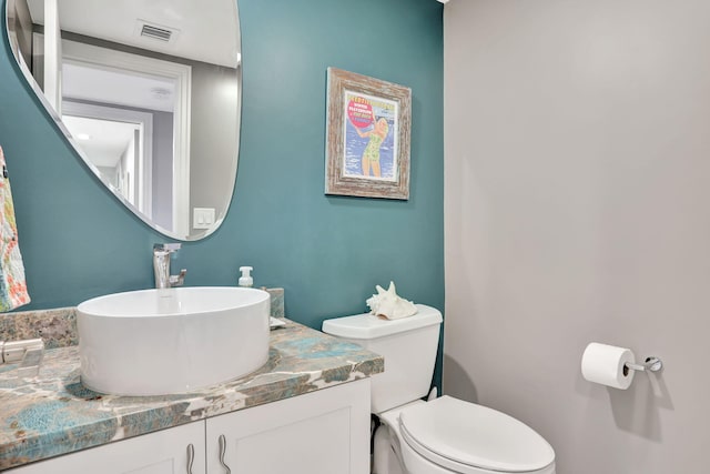 half bathroom featuring visible vents, vanity, and toilet