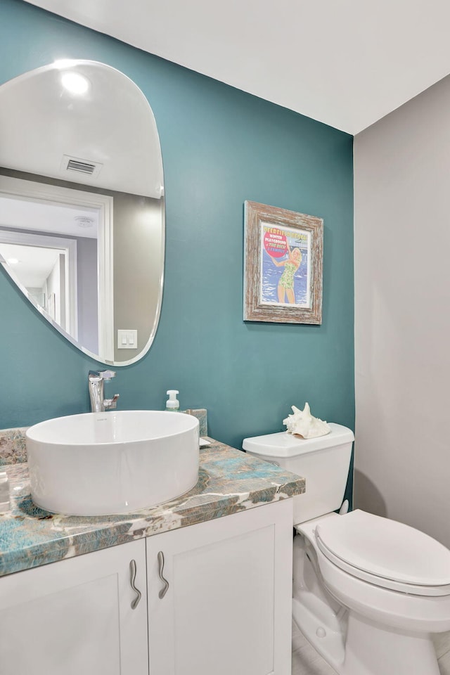 bathroom featuring toilet, vanity, and visible vents