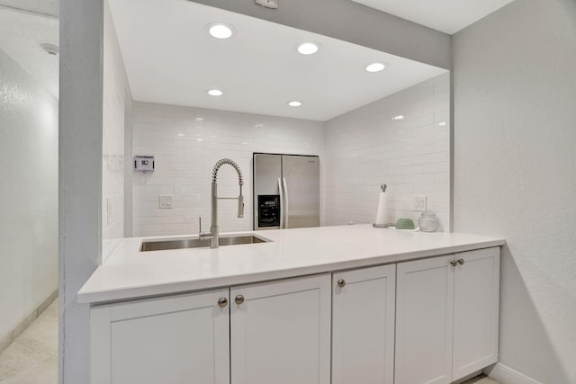 kitchen with recessed lighting, stainless steel fridge with ice dispenser, light countertops, a sink, and baseboards