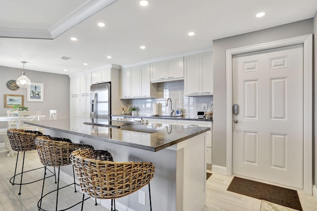 kitchen featuring white cabinets, light hardwood / wood-style flooring, a spacious island, a breakfast bar area, and stainless steel fridge with ice dispenser