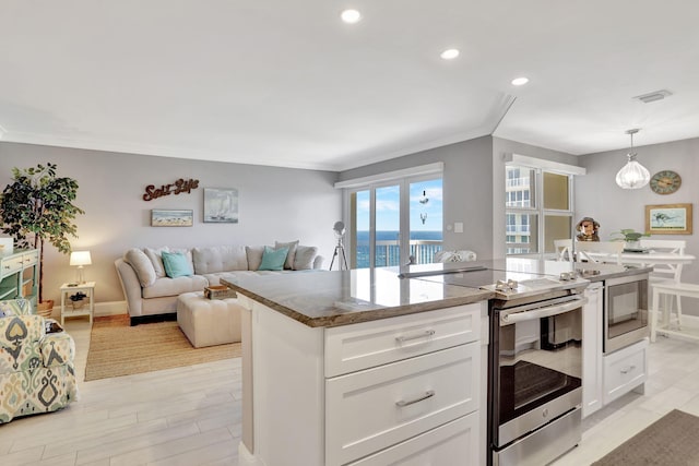 kitchen with hanging light fixtures, white cabinetry, a kitchen island, and appliances with stainless steel finishes