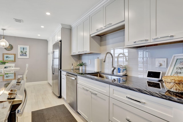 kitchen featuring stainless steel appliances, a sink, visible vents, decorative backsplash, and dark stone counters