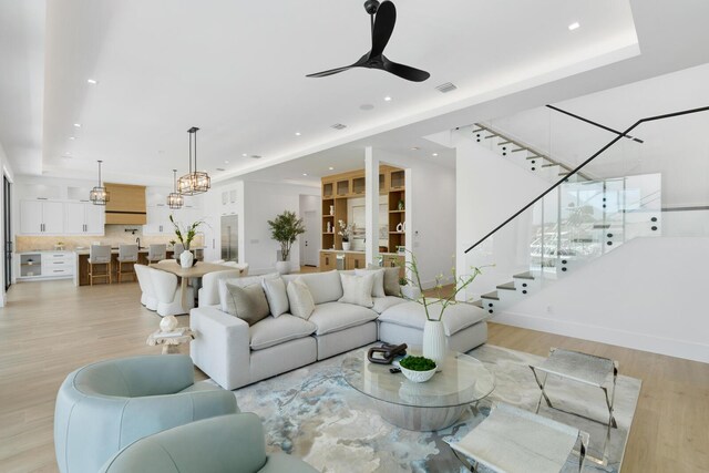 living room featuring ceiling fan with notable chandelier and light hardwood / wood-style floors