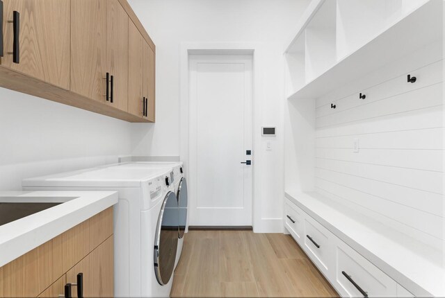 washroom with cabinets, independent washer and dryer, and light hardwood / wood-style floors