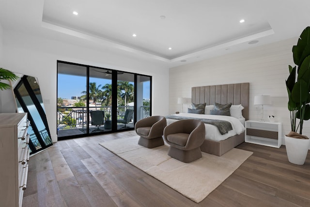 bedroom with dark wood-type flooring, a tray ceiling, access to exterior, and french doors