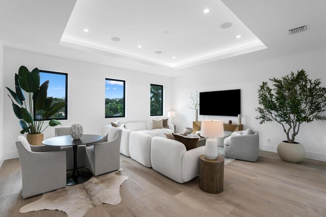 living room with a tray ceiling and light hardwood / wood-style floors