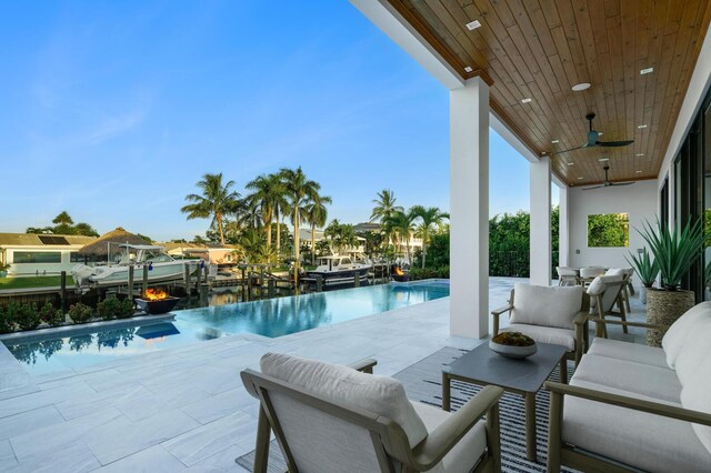 view of pool featuring an outdoor living space, a water view, ceiling fan, and a patio