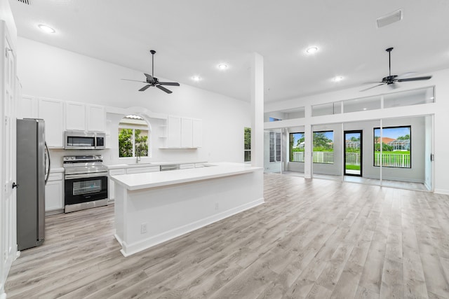 kitchen with light hardwood / wood-style flooring, ceiling fan, appliances with stainless steel finishes, and white cabinets