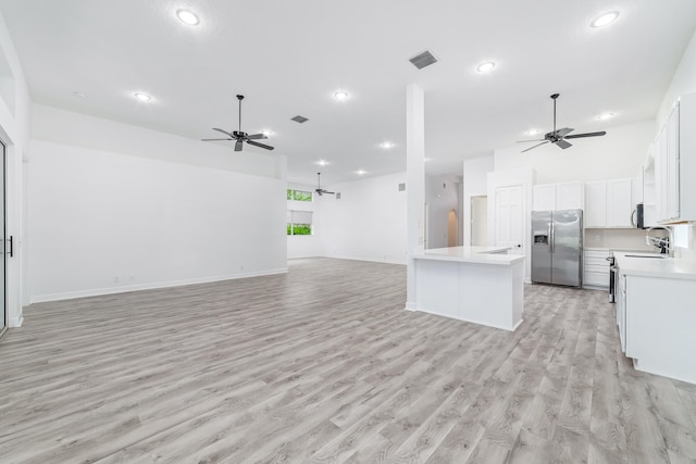 unfurnished living room featuring light hardwood / wood-style flooring, ceiling fan, and sink