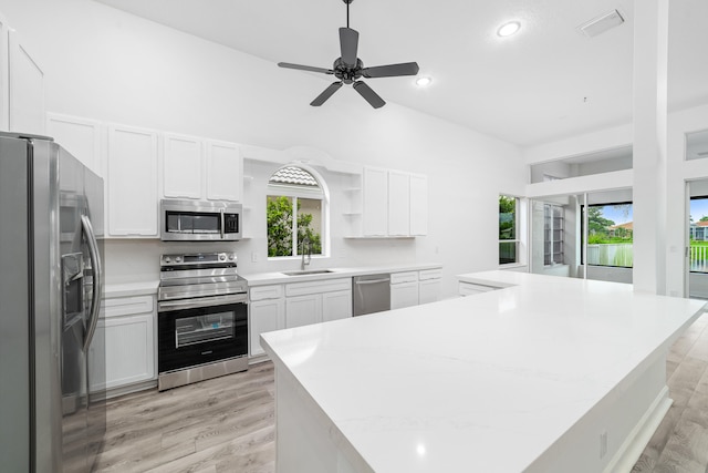 kitchen featuring light hardwood / wood-style flooring, vaulted ceiling, stainless steel appliances, sink, and ceiling fan