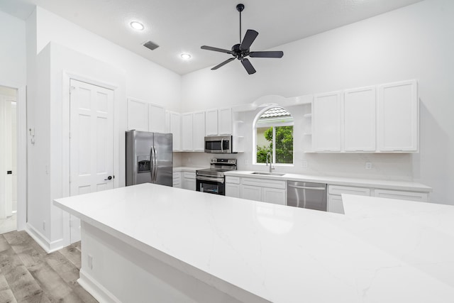 kitchen with appliances with stainless steel finishes, sink, ceiling fan, light wood-type flooring, and white cabinets