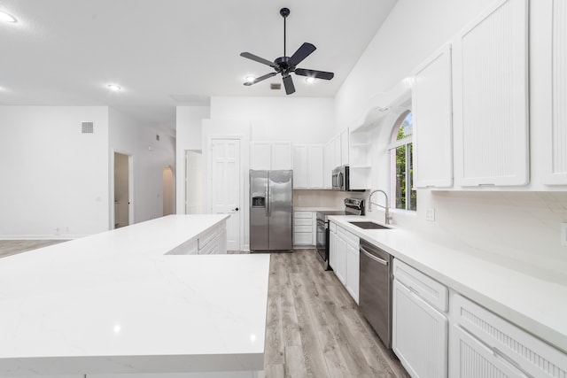 kitchen featuring stainless steel appliances, light hardwood / wood-style floors, sink, ceiling fan, and a kitchen island