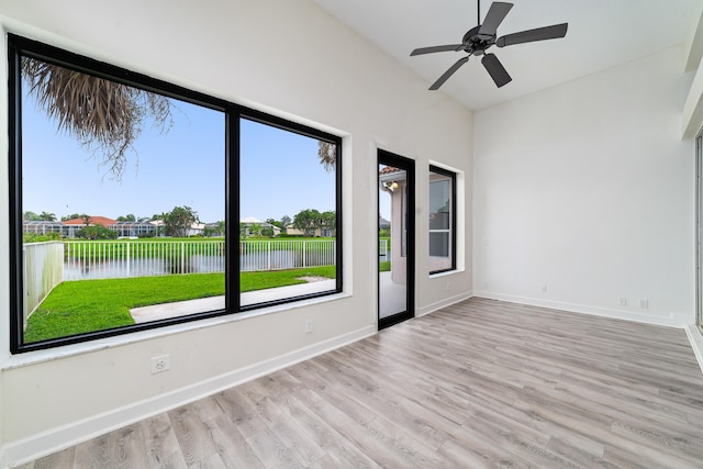 spare room featuring a water view, ceiling fan, and light wood-type flooring