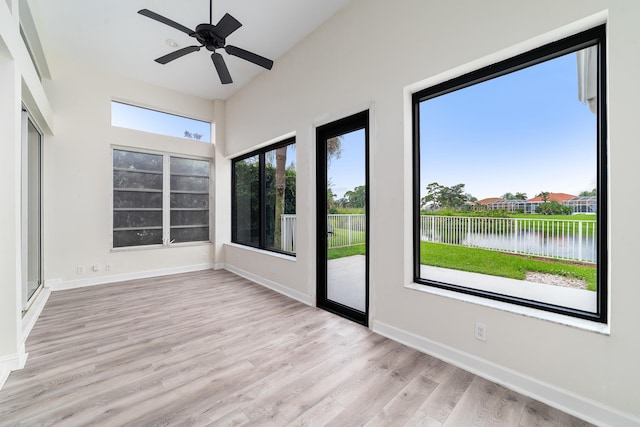 unfurnished sunroom with a wealth of natural light, ceiling fan, and a water view