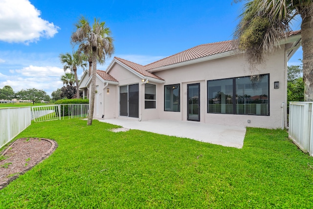 back of property with a lawn and a patio